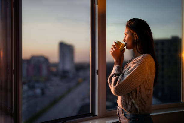Person looking out a window with soft morning light, symbolizing quiet reflection during mental health recovery